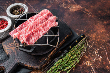 Freshly cut Wagyu flat iron steak on a rustic grill with herbs and spices, showcasing its rich marbling and premium quality.