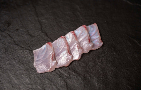 Raw fish slices on a dark surface